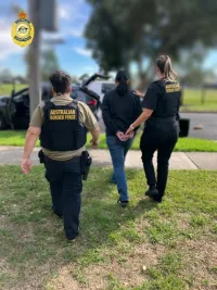 Photo of Border Force agents escorting a woman in handcuffs