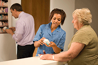 Photo of a medical practitioner talking to a patient about a bottle of medicine